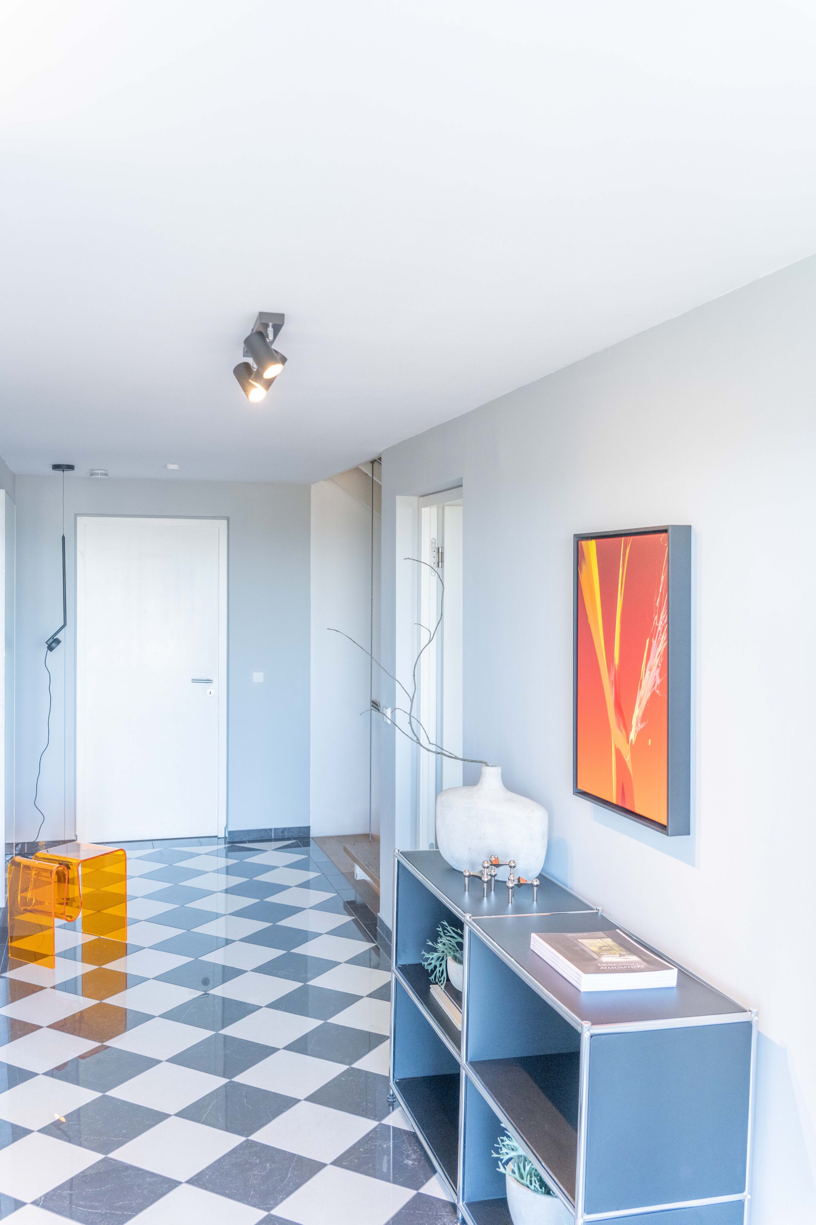Eingangsbereich einer Villa in Heidelberg-Neuenheim mit Schachbrettboden, Kunst und modernem Mobiliar.