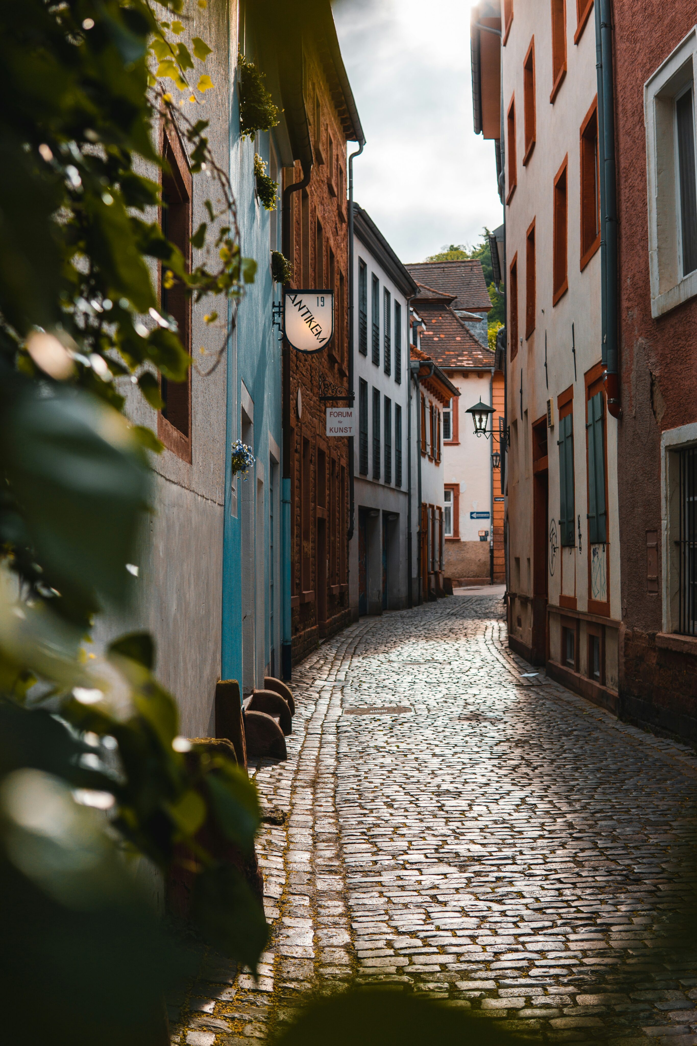 Historische Gasse in der Heidelberger Altstadt mit Kopfsteinpflaster und farbigen Fassaden.